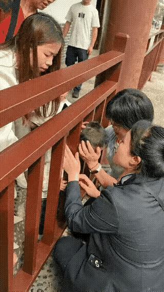 家人们，大无语事件！一个小男孩头卡在栏杆里，四个女生折腾半天没辙，结果一个戴眼镜