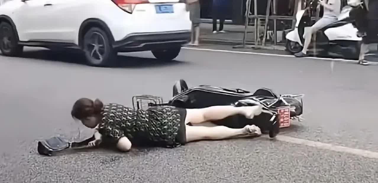 近日，四川乐山一女子骑电动车摔倒，在大街上挣扎了很久都没有爬起来，但却无人敢扶。