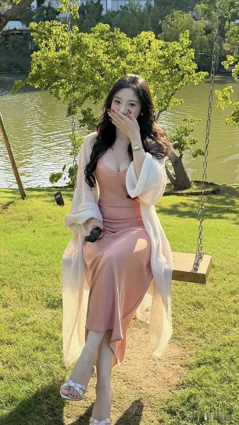 一个女孩坐在秋千上，风景很美。