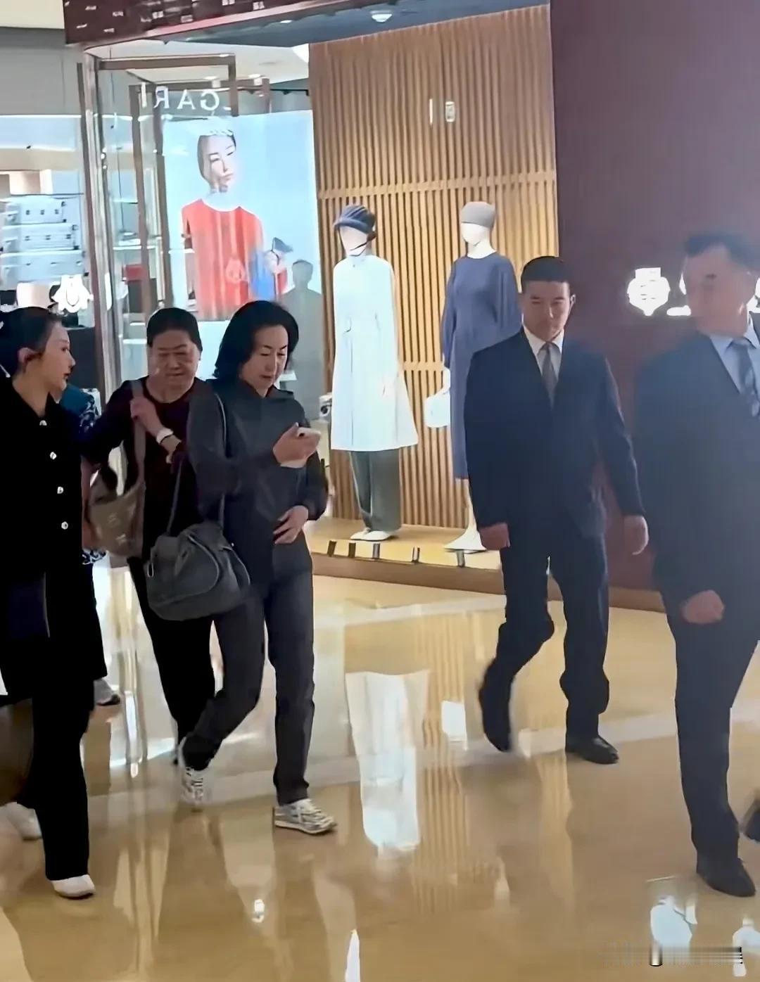 何超琼和家人现身商场购物，女强人走到哪气场都好强啊！她穿着一件灰色的连帽衣配同