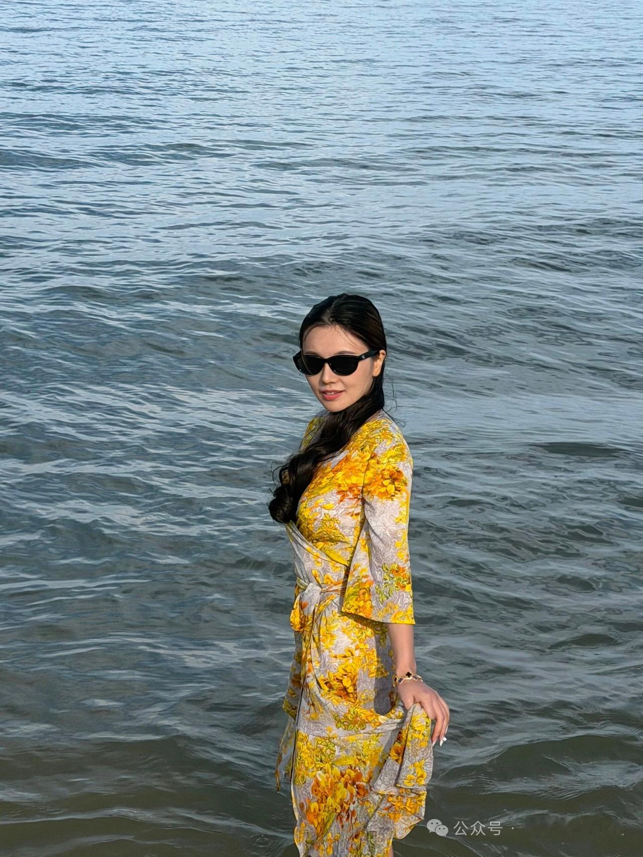 这位女士在海边拍照，穿得很漂亮。