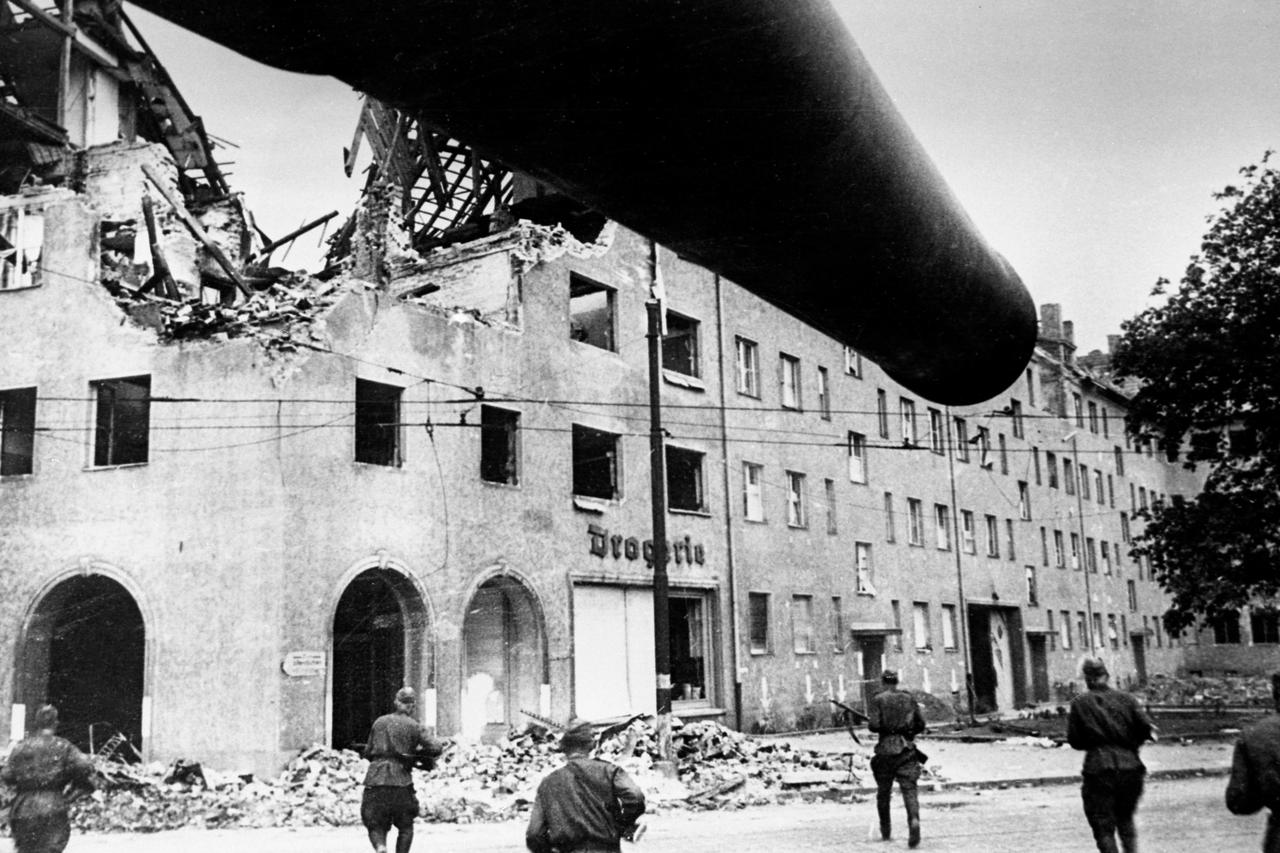 1945年，柏林战役。苏军士兵在B-4型榴弹炮的掩护下向一座被摧毁的大楼冲击