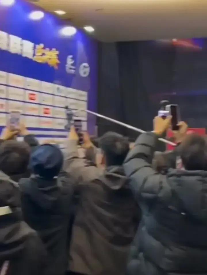 王楚钦刚走出赛场，三十多台相机几乎贴脸，随行体能师“草莓熊”被挤到三米外，连递水