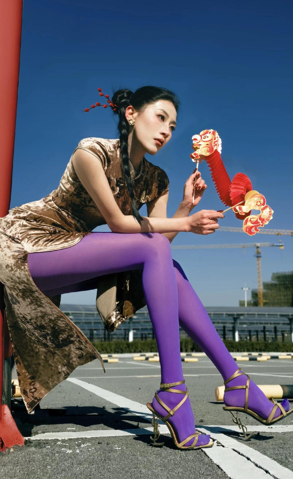 鎏金旗袍裁出曼妙风骨，盘扣间尽是古典韵味，偏偏配了一袭浮夸紫袜，大胆碰撞出别样张