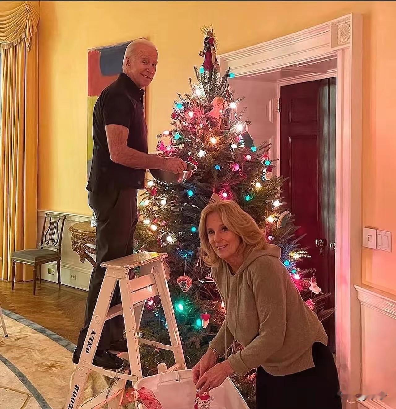 拜登和妻子吉尔一起装饰圣诞树🎄！拜登年过八旬，穿着黑色T恤，虽然满头白发，但