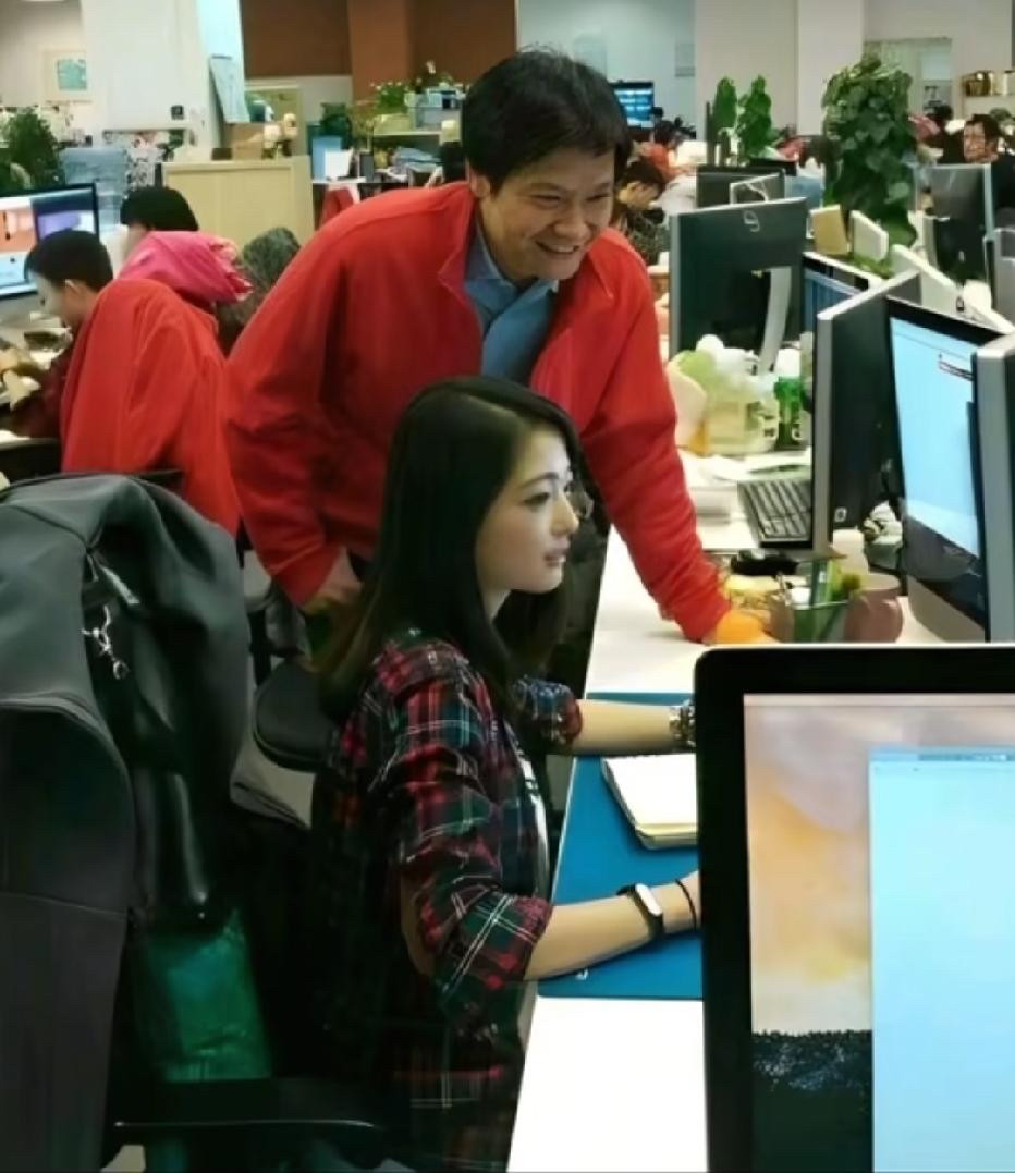 2014年，小米正值创业上升期，一张雷军俯身与员工交流的照片在网络上悄然流传。画面中，雷军站在一位女
