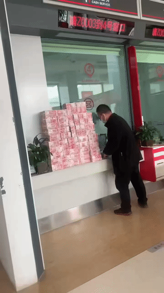 银行里拍到一位土豪大叔正在存钱！成捆成捆的现金钞票像小山一样摆在银行柜台窗口？