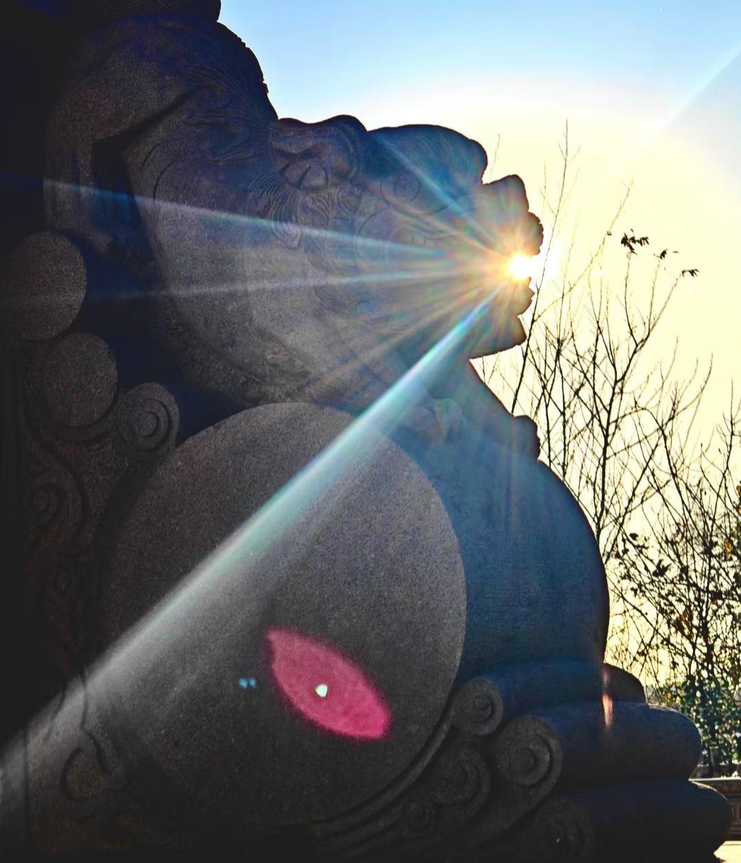 石兽衔住了落日的金芒，把光的碎屑泼向古拙的纹路，连那抹艳红，都成了光阴里灼目的诗