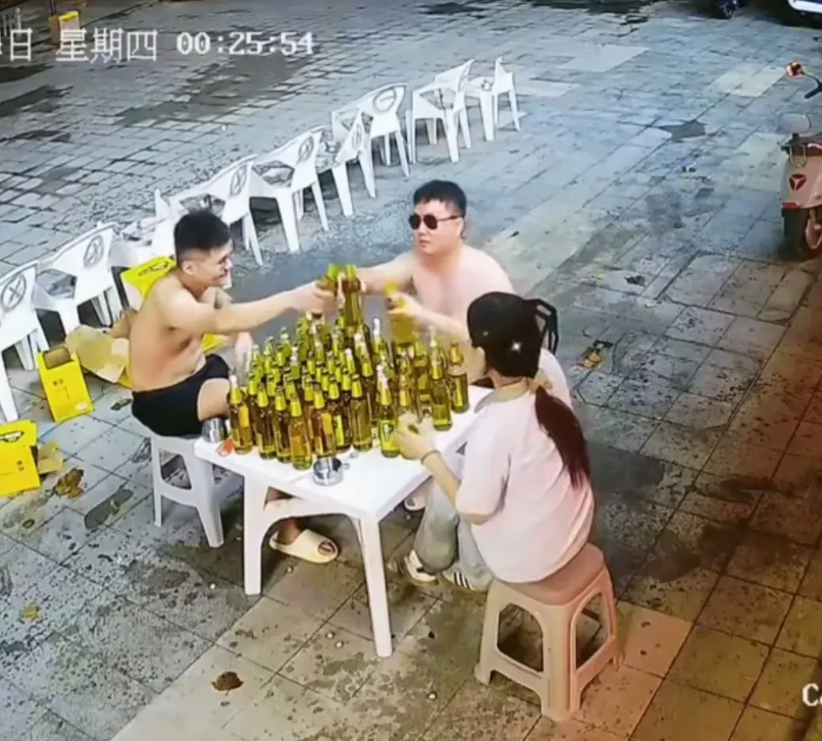 近日，在济南一家饭店的门口，两名光膀男子和一名女子，坐在一个桌前，桌上摆满了啤酒