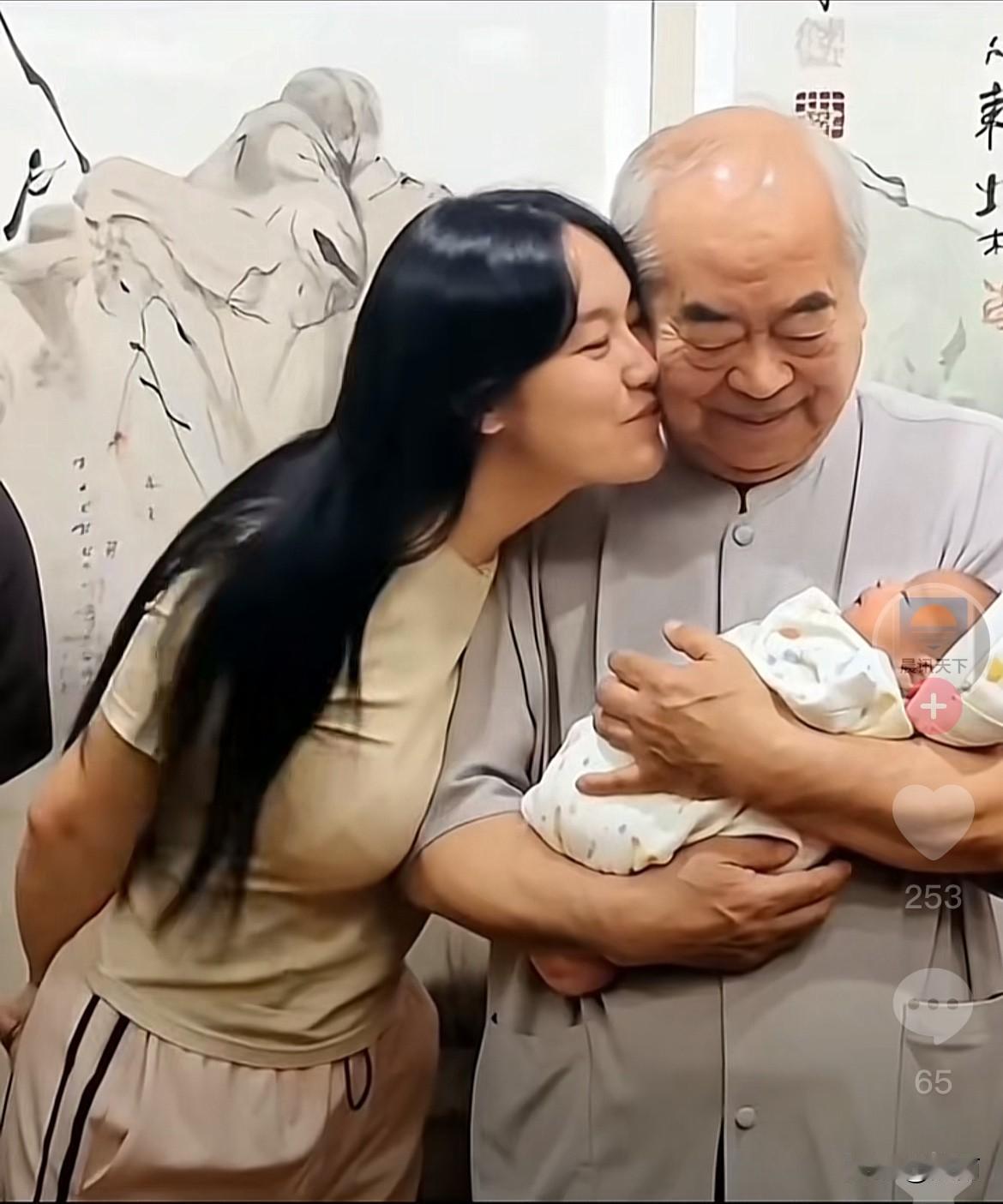 人逢喜事精神爽。老来得子的范曾用慈爱的眼神看着怀抱中的儿子，媳妇徐娇轻轻的亲吻着