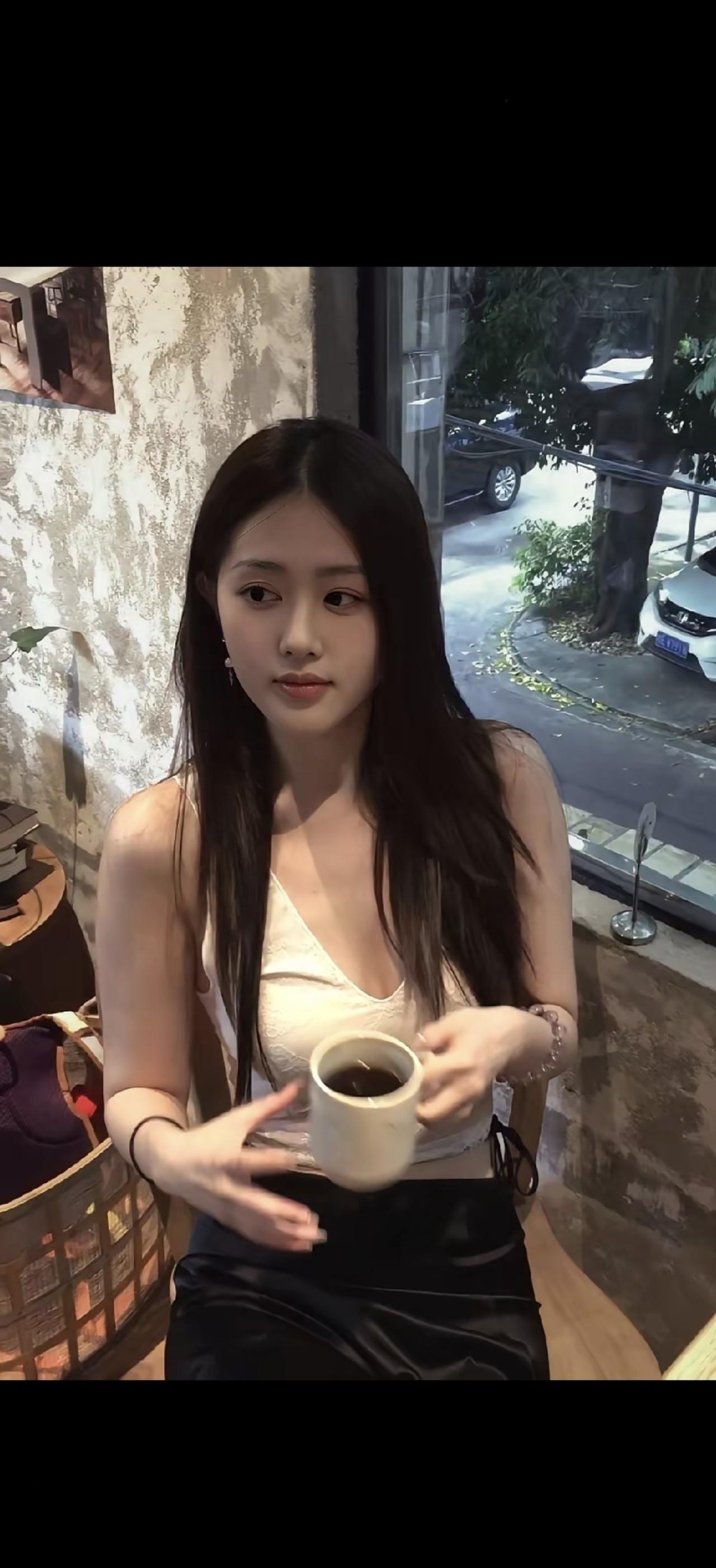 美女在咖啡馆喝咖啡，窗外有树和车。