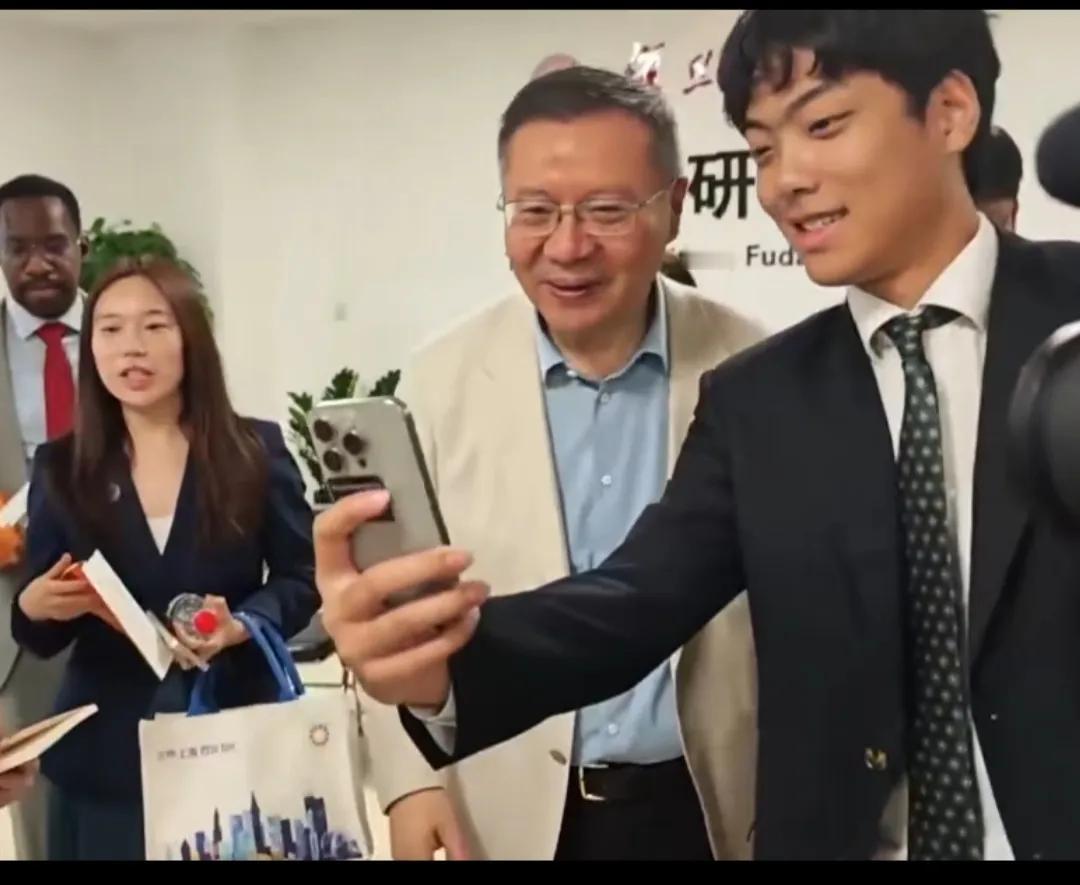 张维为，即将迈入古稀之年的映照。这是张维为教授与来访学生的合影图片。当某人与张