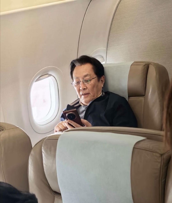 73岁唐国强在飞机上被偶遇，他坐在头等舱，翘着二郎腿看报纸，一副领导出行的派头，