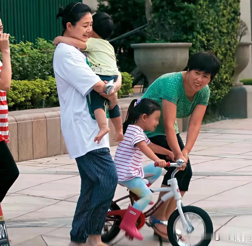​小杨阿姨在教玥儿骑自行车，大S就在旁边一边注意玥儿的安全，一边抱着霖霖。​看