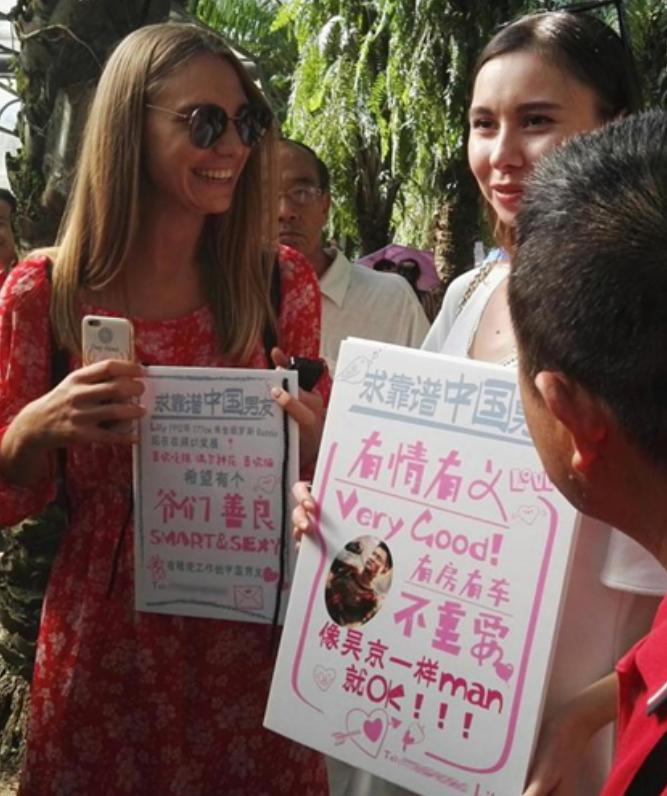 两位外国姑娘直接扎进相亲角举牌找对象，要求写得格外实在：一个只要爷们、善良、有稳