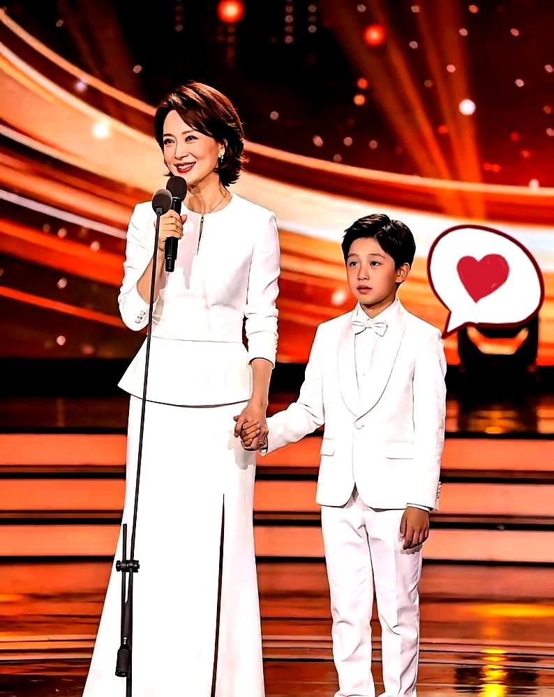 51岁的董卿，罕见露面，竟是在儿子学校的小礼堂里。她一袭白裙，和穿着小白西装