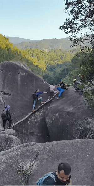 棍子上的女子:哇哇！哎哎哎！哎呀！站在石头上男子:这声音好听！穿着瑜伽裤来爬