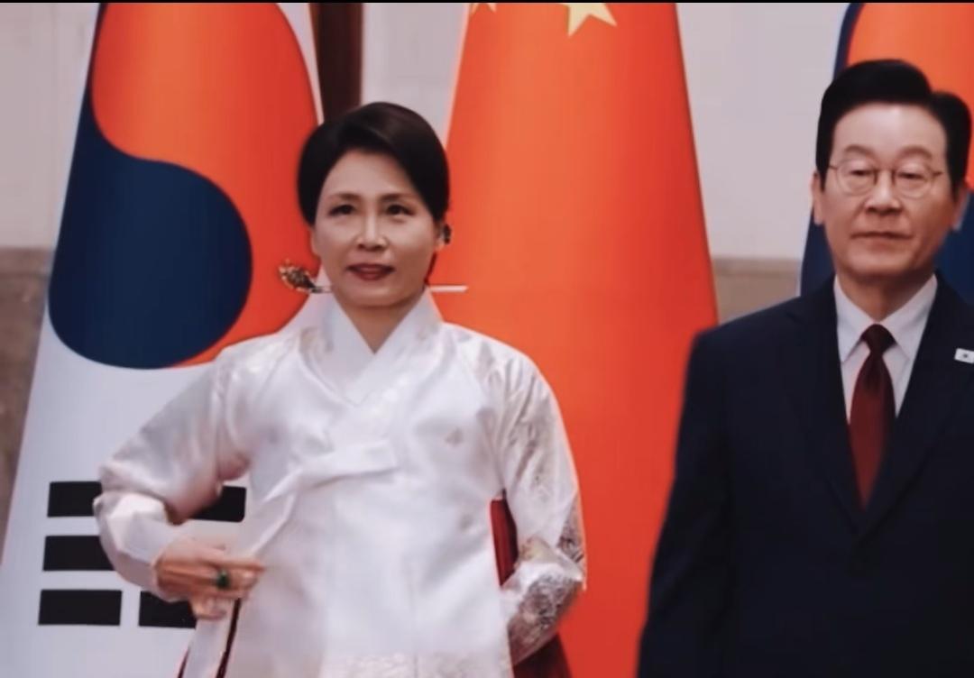 红毯上，那抹红色裙摆划破空气——白色上衣紧贴，绿宝石戒指冷光一闪。双手始终藏袖