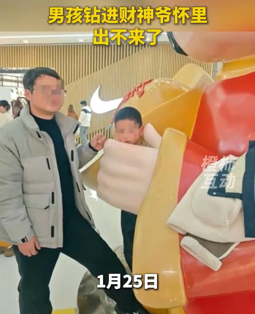浙江义乌，家长带着孩子去商场游玩，男孩看到商场的“财神爷”雕像有趣，就把身体钻了