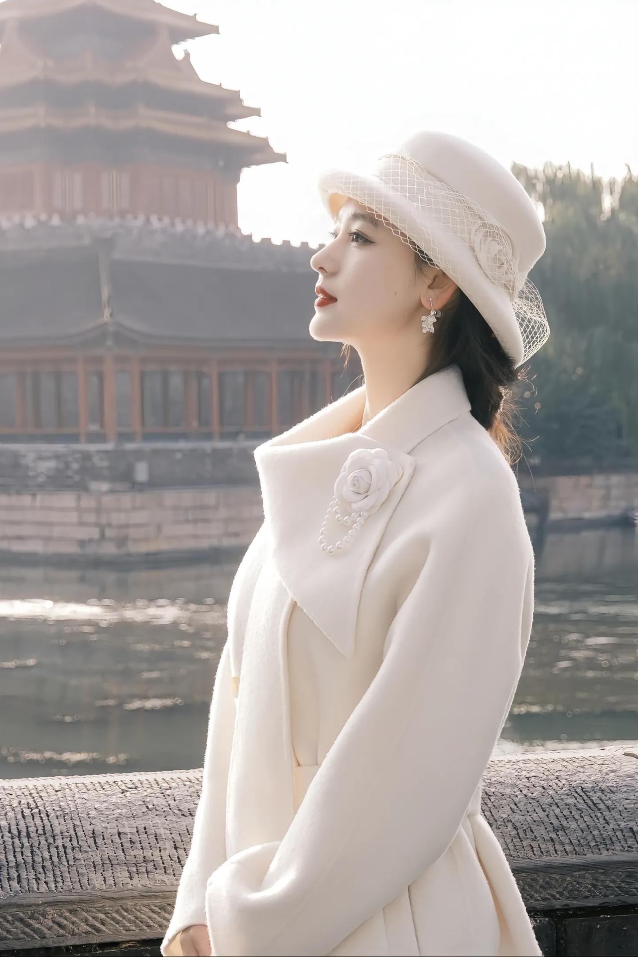 优雅的白色大衣，搭配复古的白色帽子，在古老的建筑前，尽显时尚与古典的完美融合。