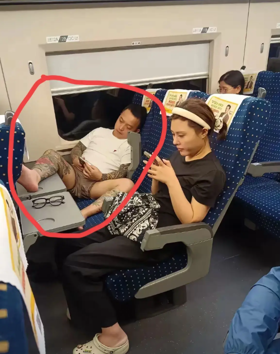 高铁上这个纹身男子实在太过分了！他穿个裤衩，把腿放在桌面上，脚都要伸到旁边姑娘脸
