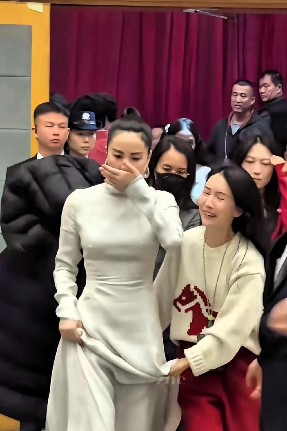 王菲在春晚后台前呼后拥、气场强大。她穿着一件白色套裙，身材苗条错落有致，一点也不