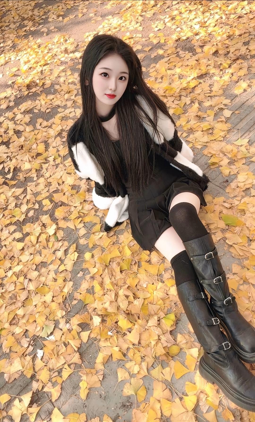 秋日暖阳下，落叶铺满地，少女轻坐其上，静享美好时光。