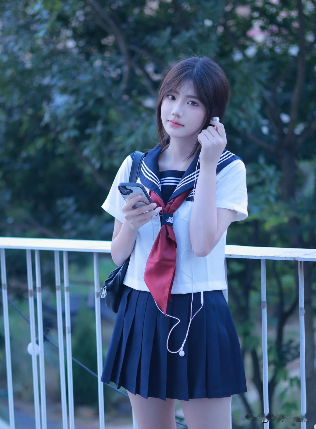 穿着水手服的女孩在听耳机。