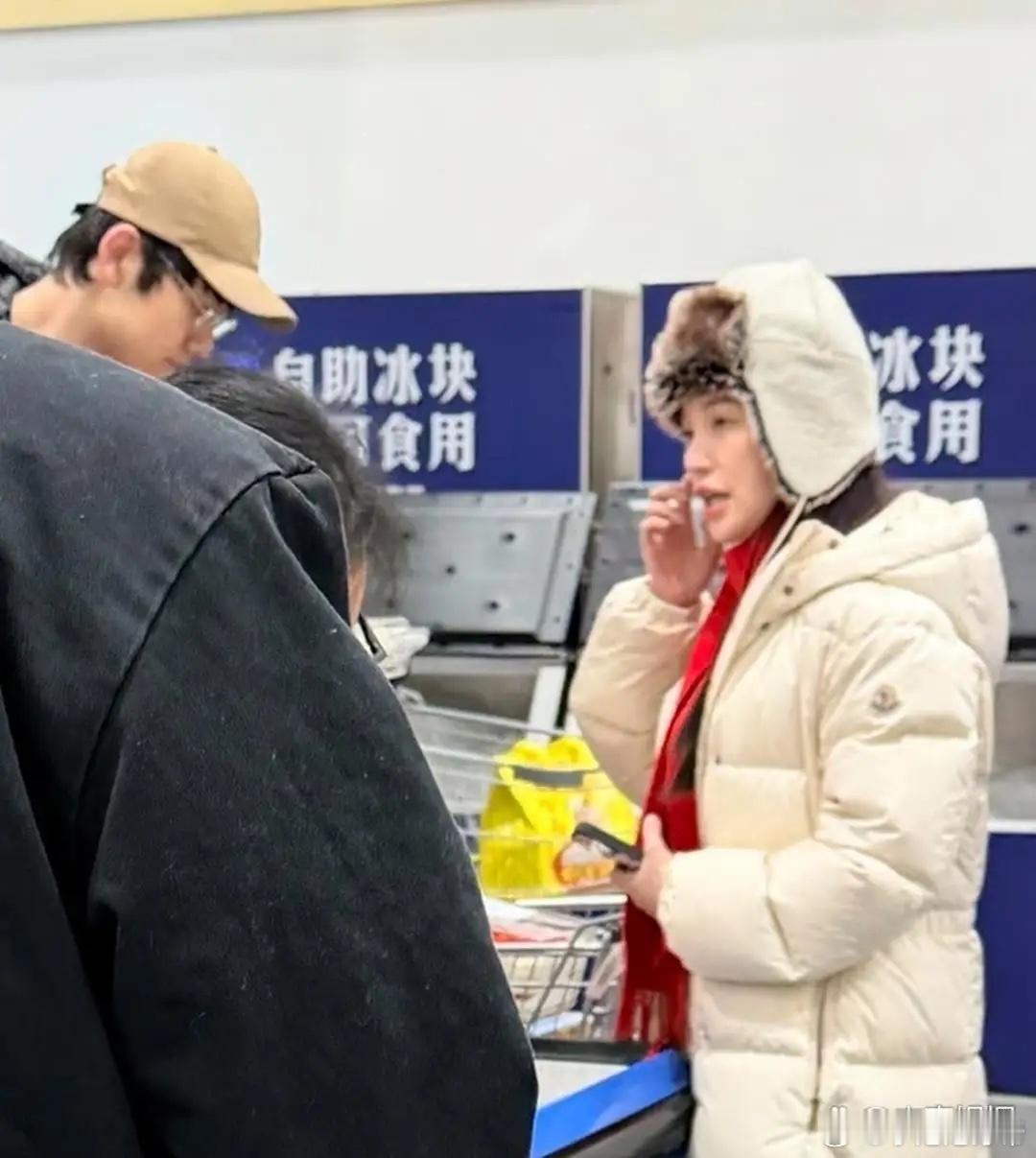 44岁金莎和未婚夫孙丞潇现身上海某商场购物被偶遇，她穿了一件米色羽绒大衣，系着红