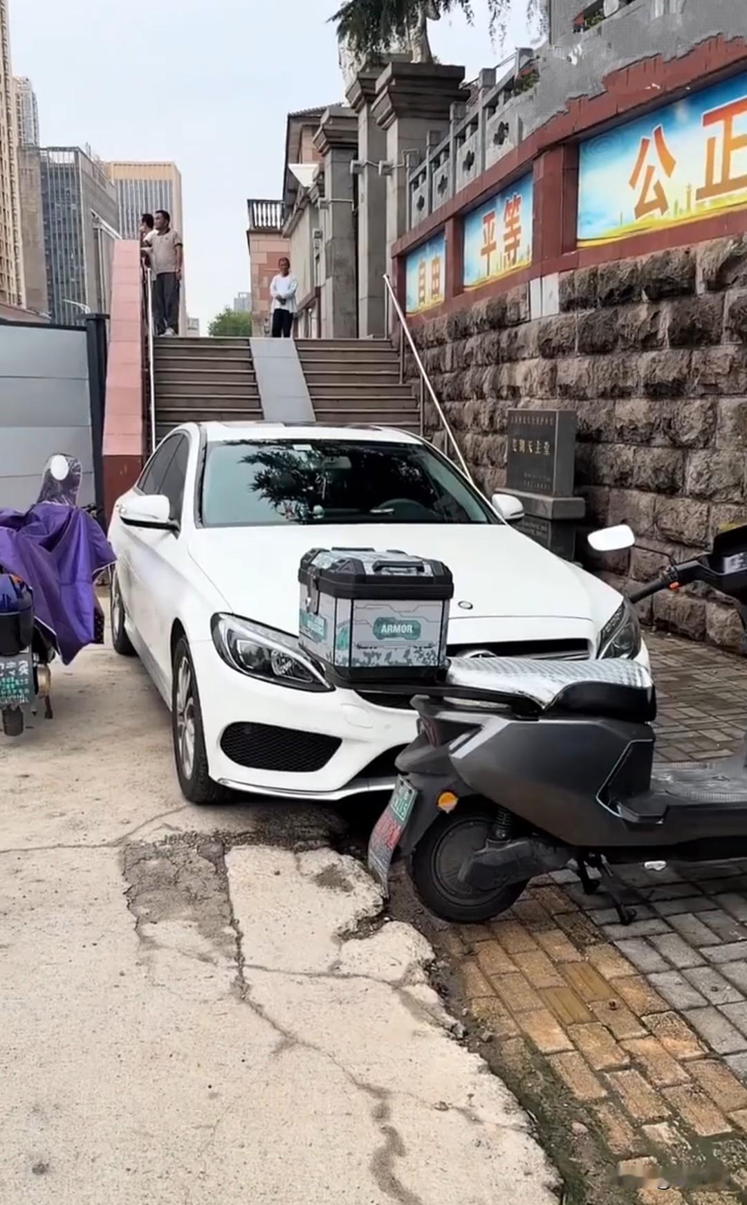 女子把车停在台阶前，上下台阶的路被堵得死死的，两辆电动车干脆停在白车正前方，把她