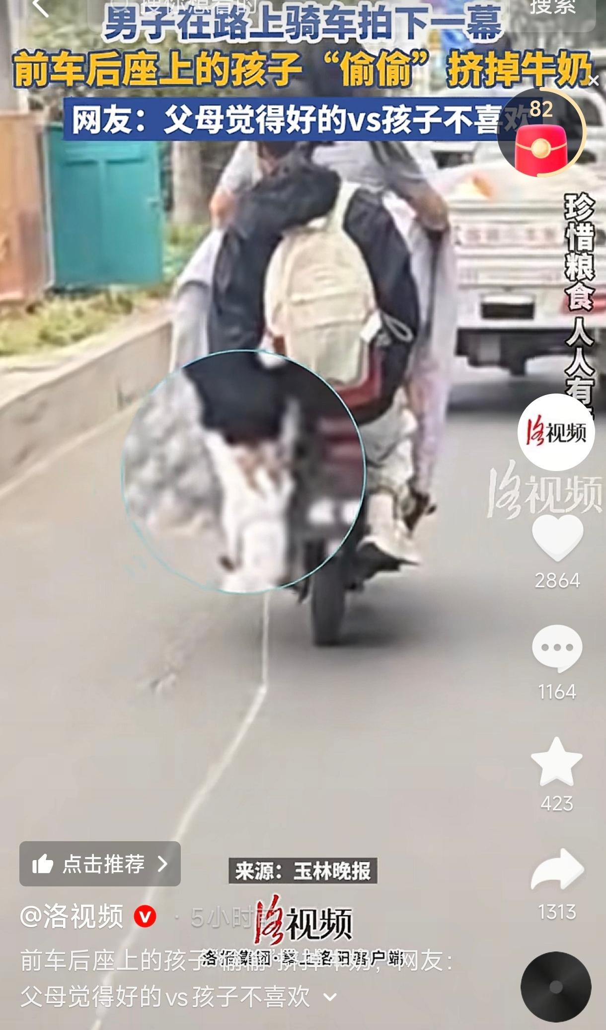 河南街头，一女子骑着电动车带着孩子，而后座上的孩子趁妈妈专心骑车，悄悄把手中的牛