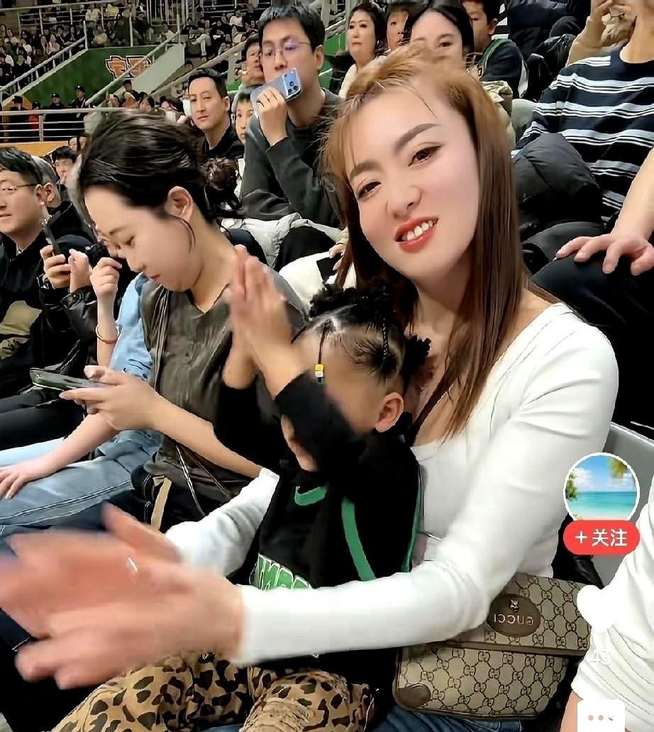看台边，他女儿把熊猫玩偶举过头顶，妻子用手机对着孩子咧开嘴笑。与此同时在场上，