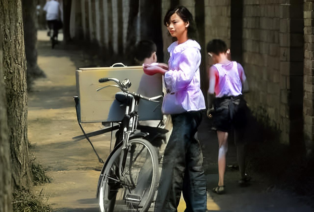 这是1982年北京胡同里的冰棒西施。这名冰棒西施不仅颜值很高，装扮也非常时髦。她