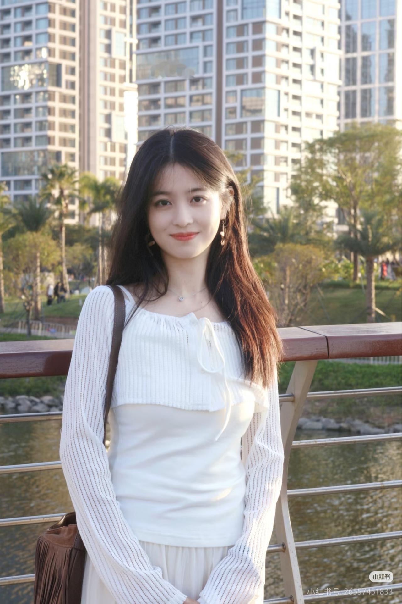 白衣少女倚栏杆，城市绿意映笑颜。