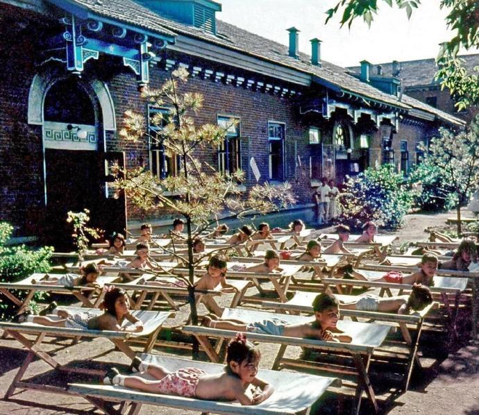 这是1959年沈阳工人新村幼儿园的娃娃们穿着裤衩躺在院子里各自的小床上享受日光浴