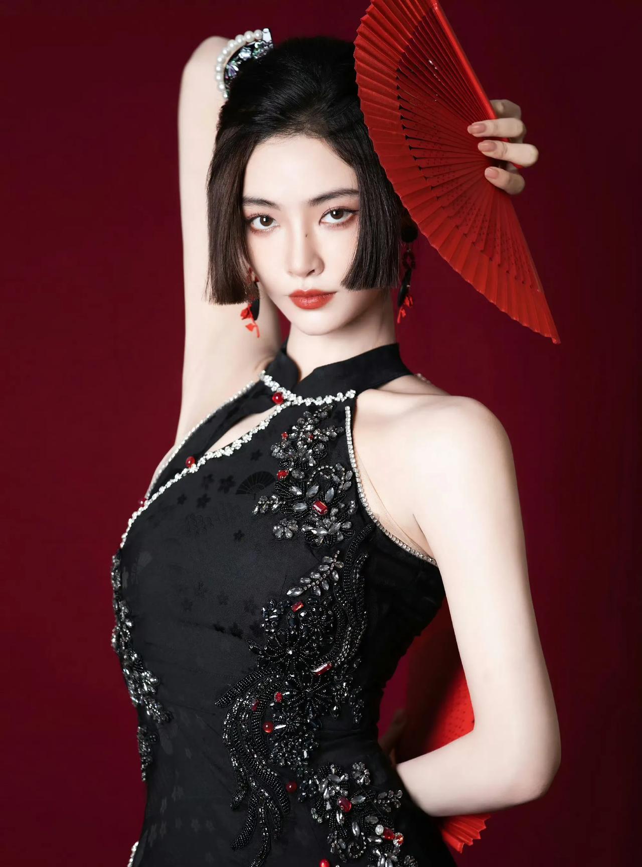 一袭黑旗袍，珠绣添华丽，手持红扇，许佳琪于深红背景前，尽显东方韵味。姿态百变，或