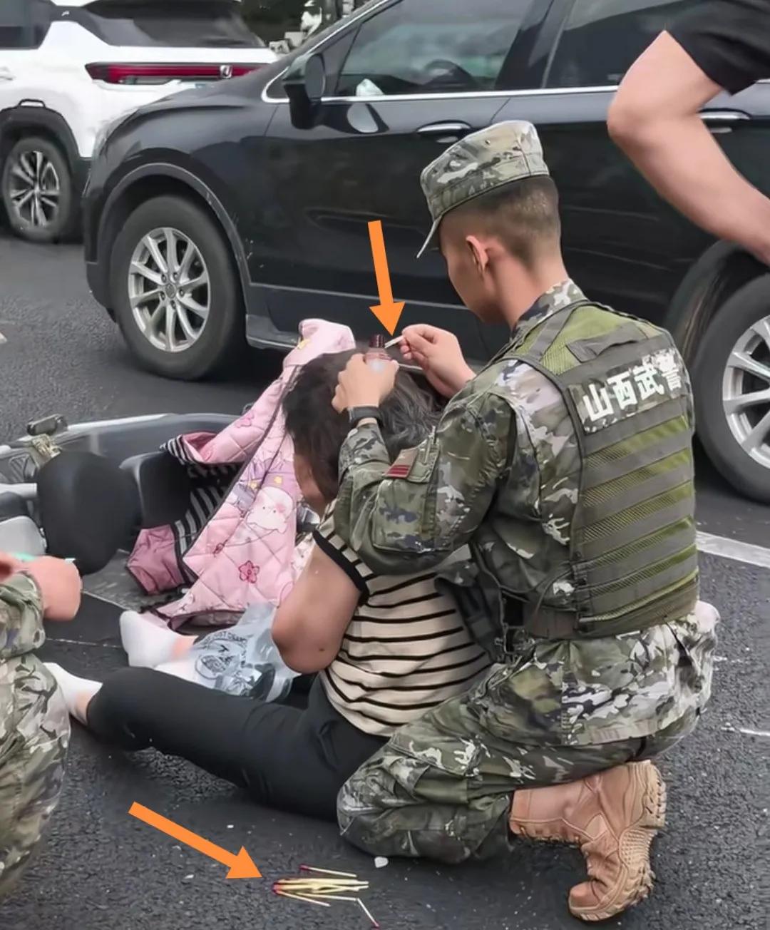 街头“陕西武警”单膝跪地一手拿棉签一手拿药水给受伤妇女头部处理伤口。
