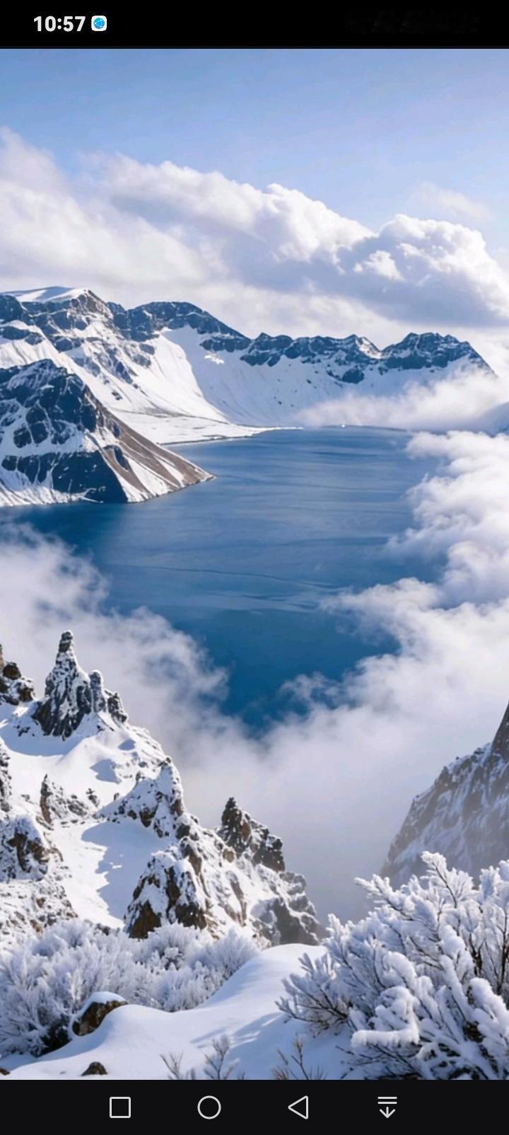 冬日的长白山天池，像一块被雪山捧在手心的蓝宝石。澄澈的湖面与皑皑雪峰相映，云海在