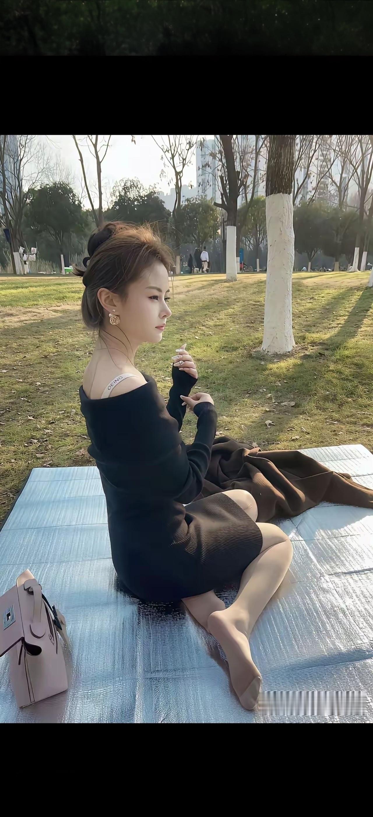 美女坐在公园草地上晒太阳。