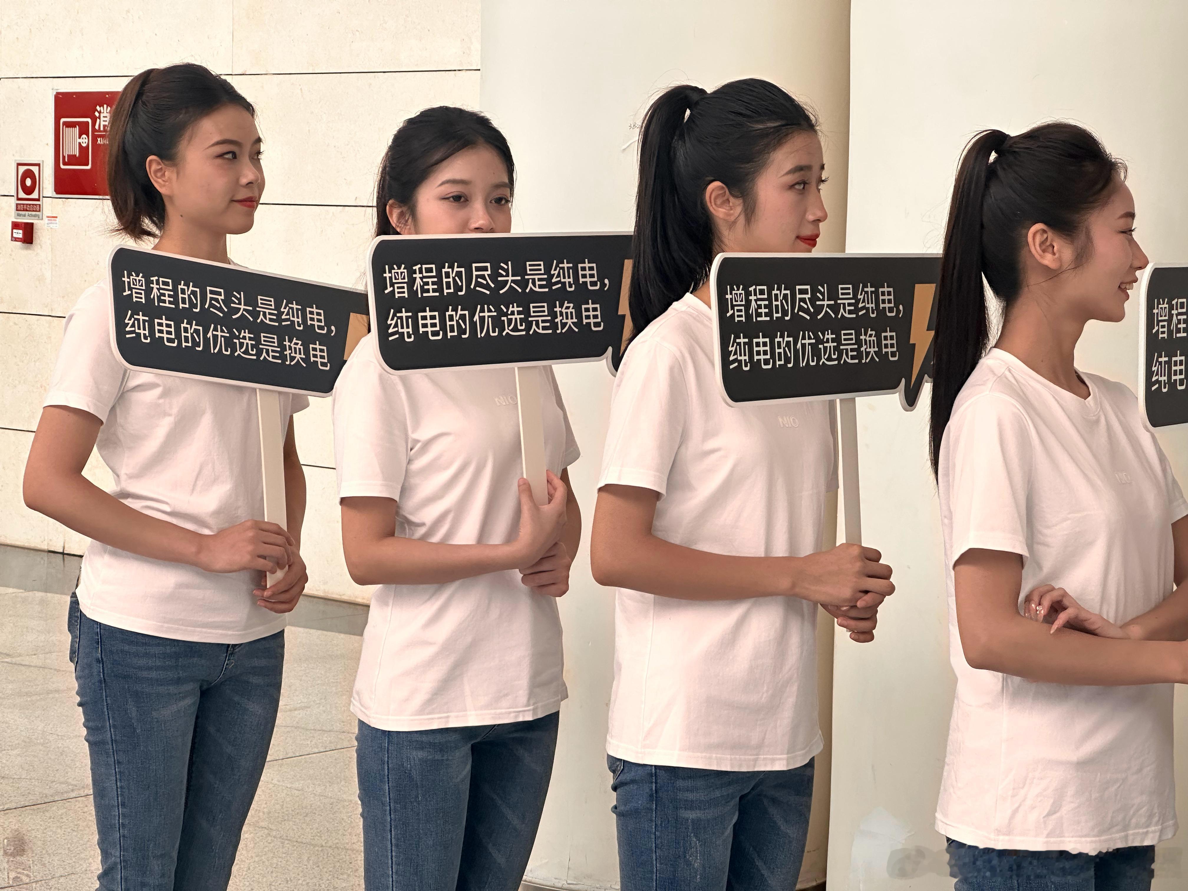 成都车展三号馆顺手拍，这组小姐姐就站在三号馆门口。牌子上写着：增程的尽头是纯电，