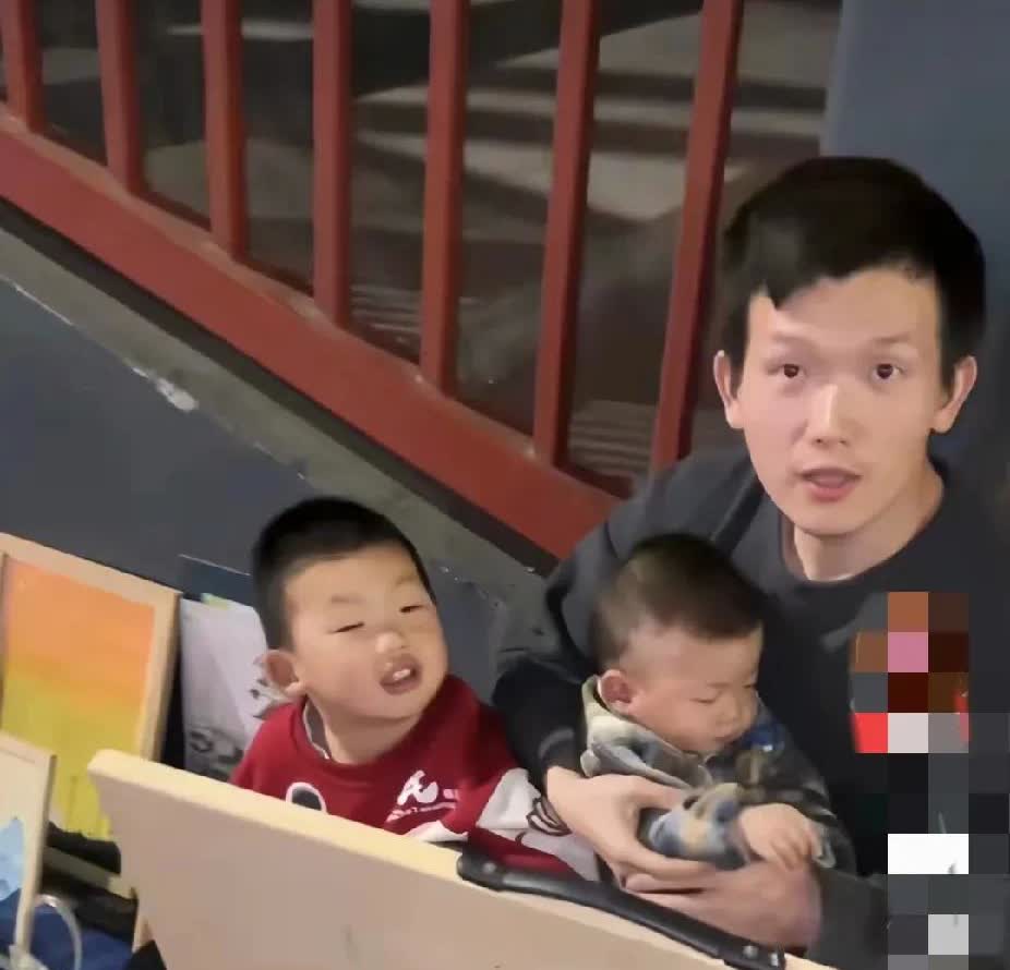 深夜的长沙街头，一男子带着两个娃摆摊卖画，怀里抱着一个一两岁的孩子，边上坐着三四