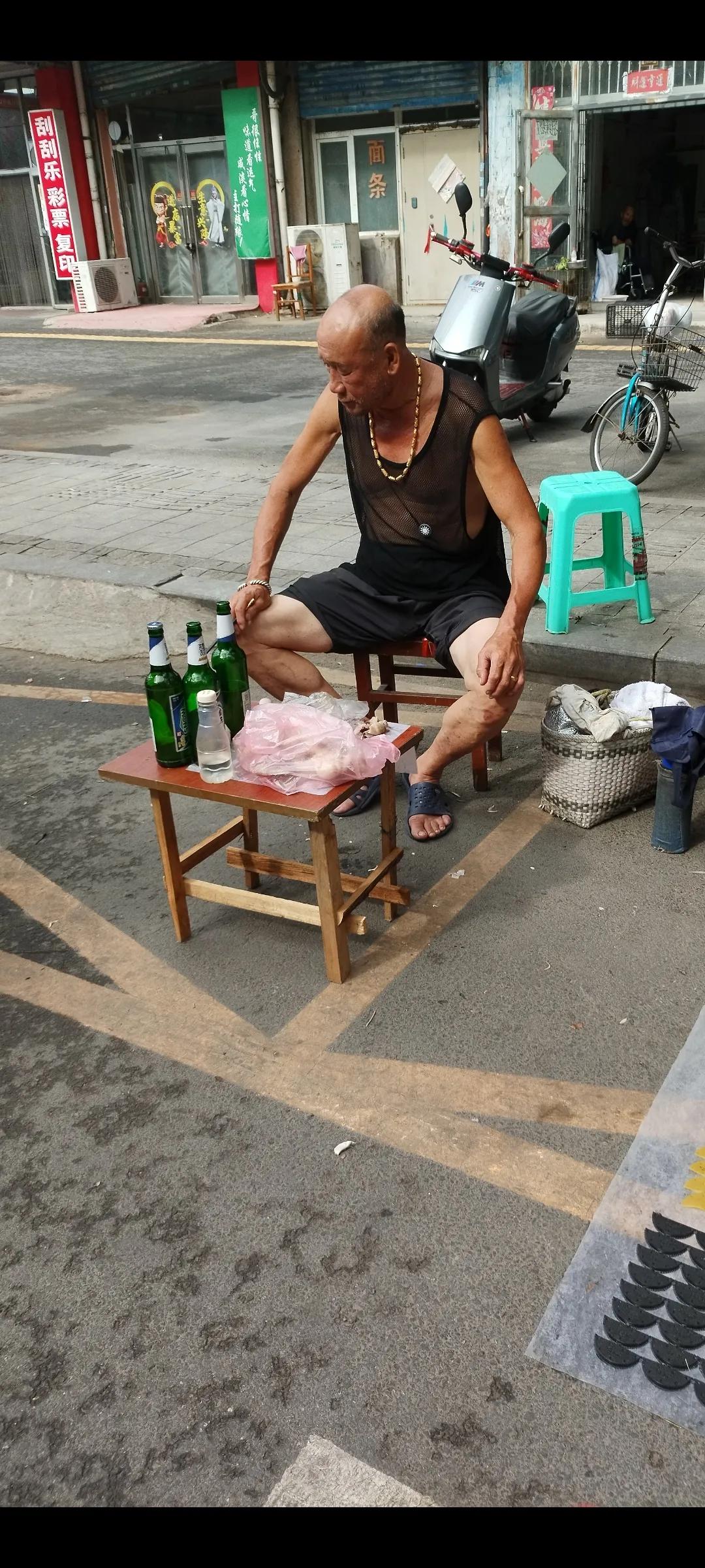 在一个小饭店门口看见的。坐在凳子上，前面放个简单的一个小桌子。桌子上三瓶