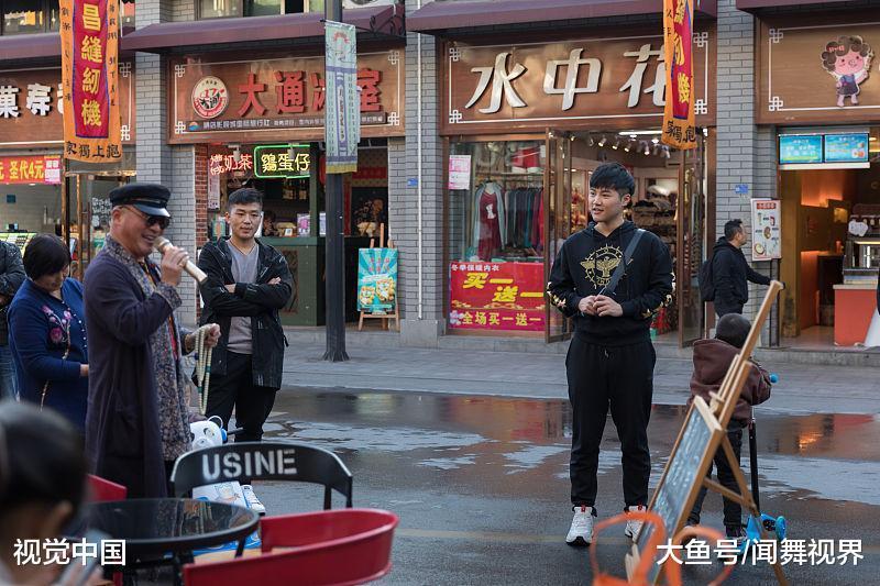 图为在步行街,街头艺人引起庄宏宇驻足观看.