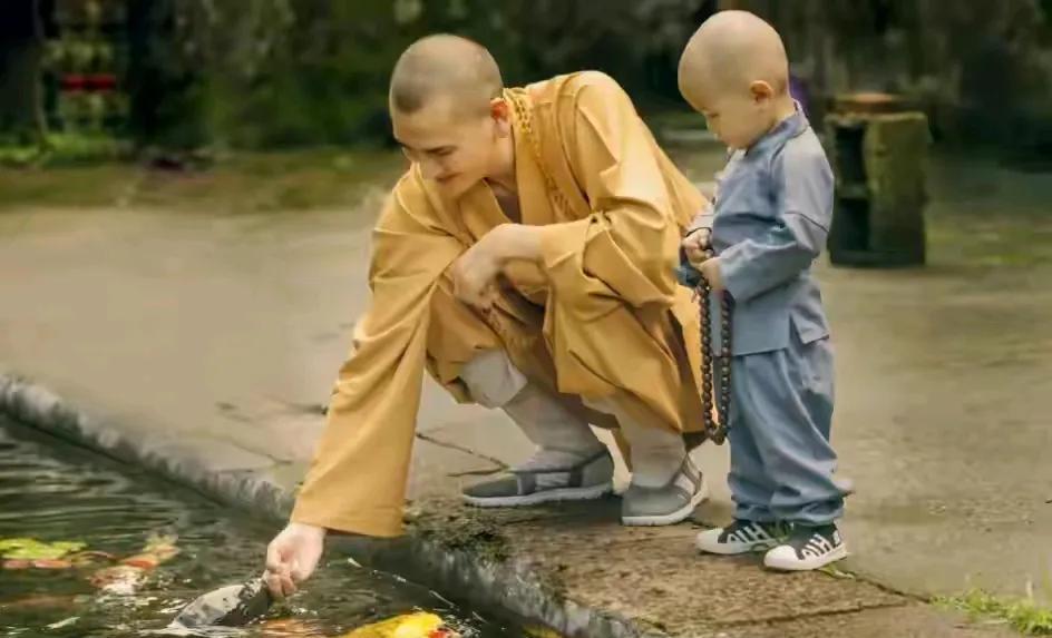 释明心身旁有位小和尚，这么小的孩子就出家了么？以后长大了他看到和释明心合影的女子
