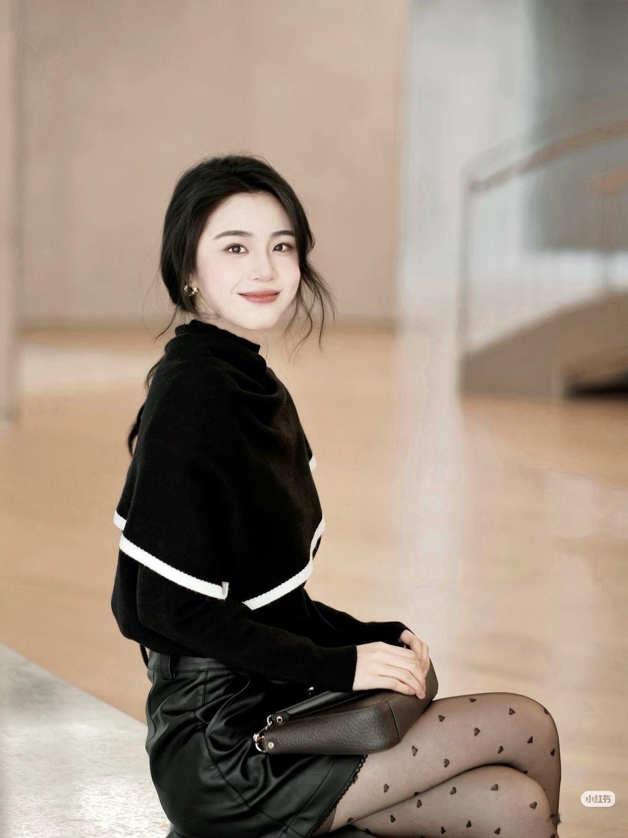 优雅黑衣少女，微笑坐于现代空间