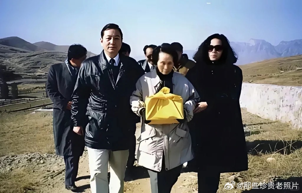 1995年1月，溥仪遗孀李淑贤手捧黄绸包裹的骨灰盒的留影。旁人搀扶着心情沉痛的她