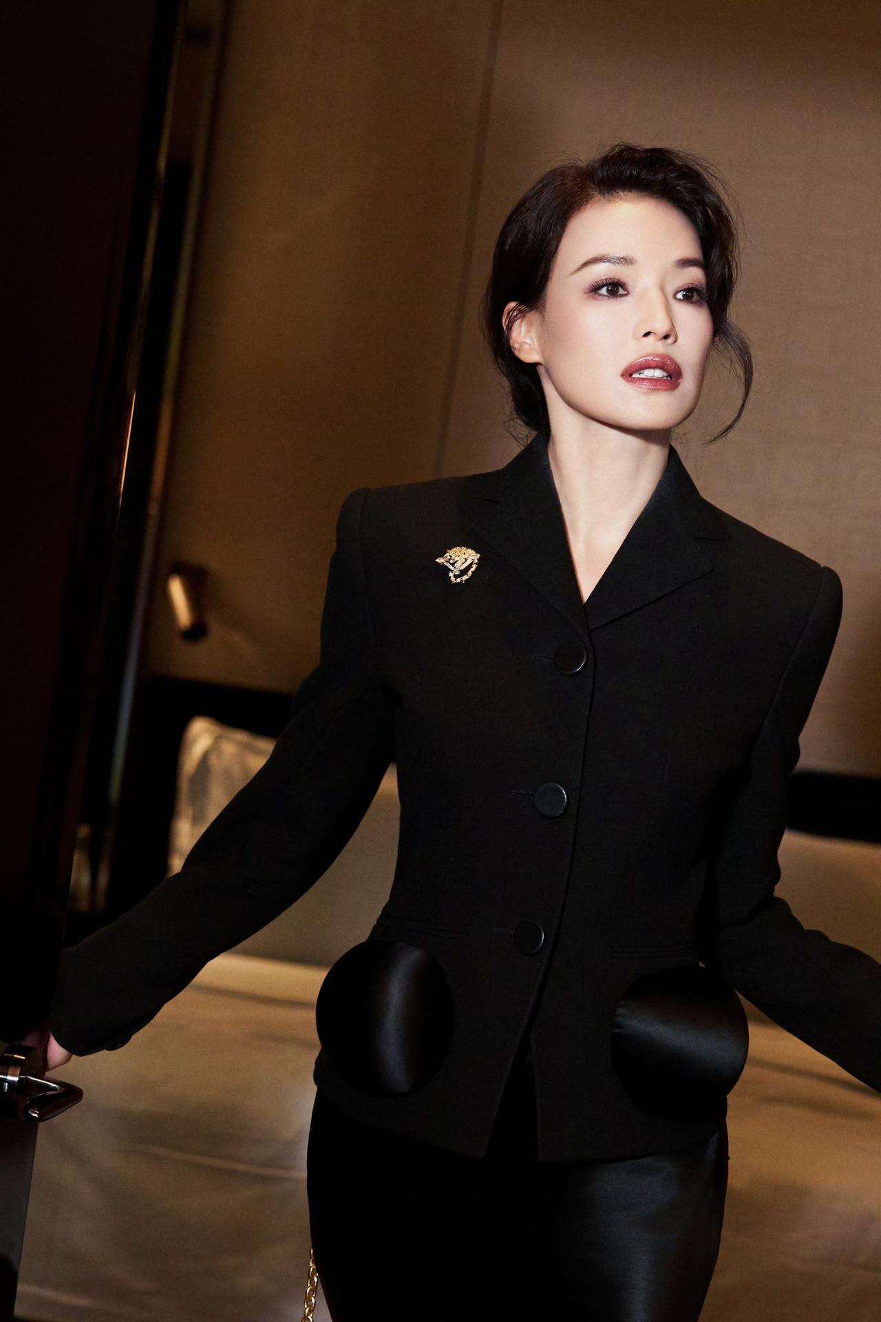 暗调光影里，一袭黑西装与缎面长裙碰撞出优雅锋芒，复古胸针点缀细节，每一步都带着不