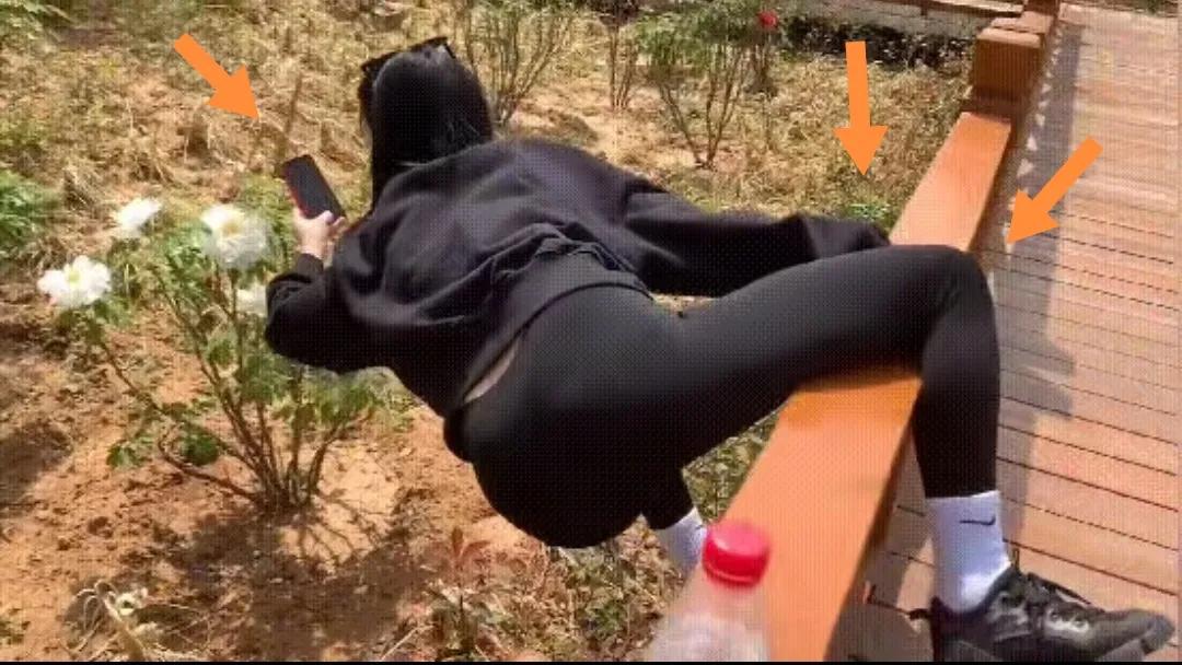 一穿黑衣女子单手腿挂桥手机拍照白牡丹花儿。