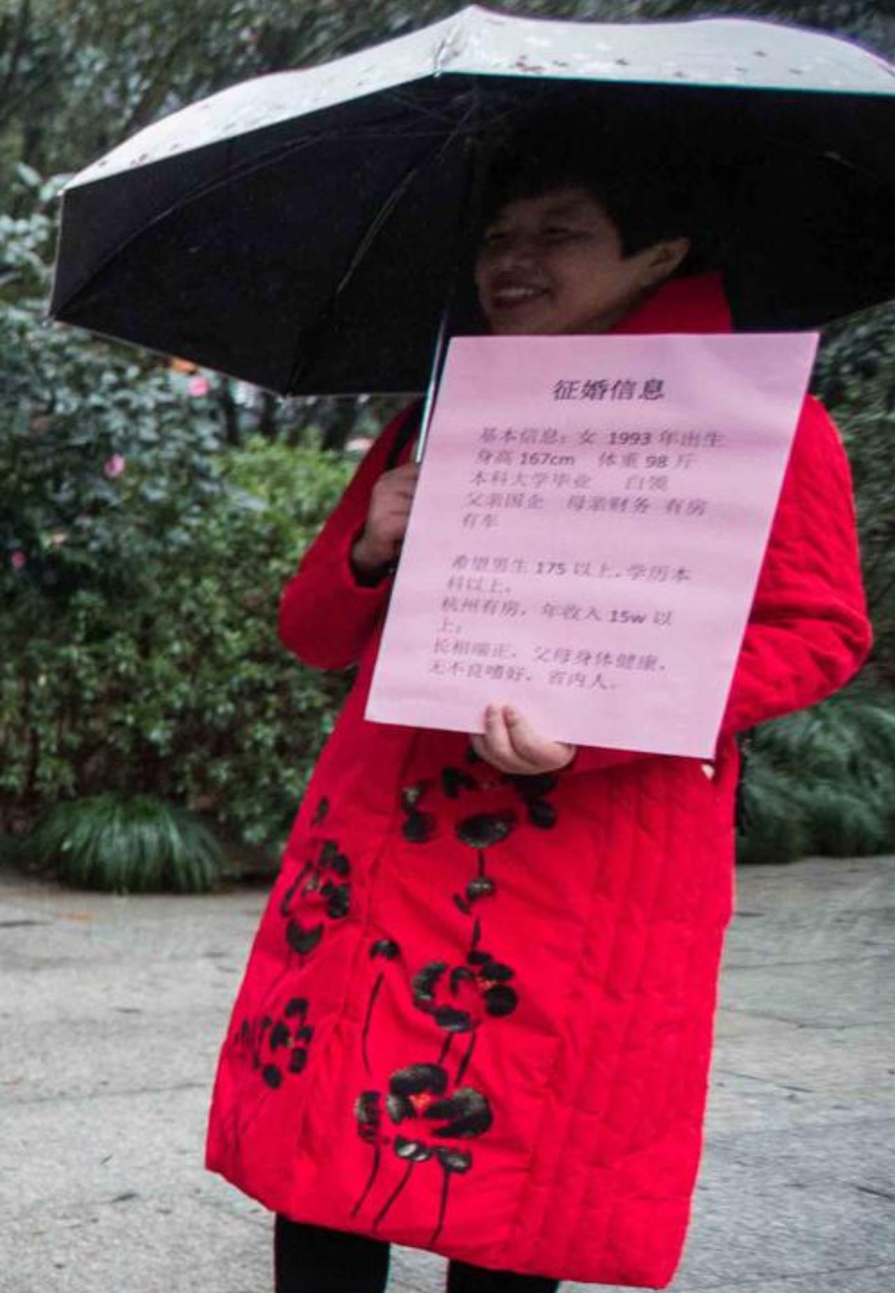 阿姨撑着伞，开开心心举着姑娘的征婚牌，条件一条条写得明明白白：男生一米七五以上、