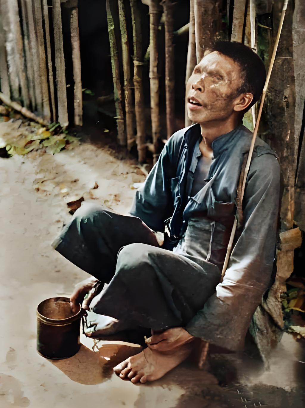 在民国的灰暗街头，一位盲人乞丐静静坐着。破旧衣衫遮不住生活的沧桑，赤脚、简陋铁罐